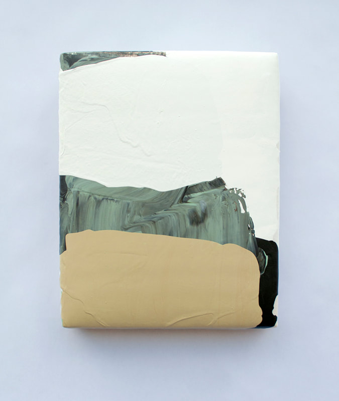 An upholstered vertical painting with layers of white, tan and black pours with a weight to the bottom of the painting in terms of composition